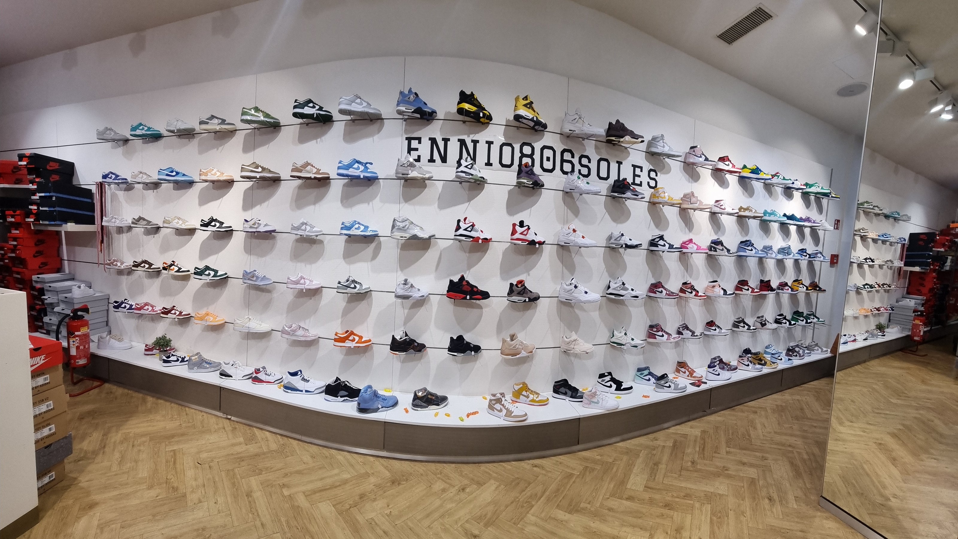 die schuhwand mit allen sneaker modellen von links (nike dunks) bis rechts (air jordan 1) und dazwischen einige jordan 4 und adidas campus modelle. der laden ist für halloween dekoriert mit süssigkeiten