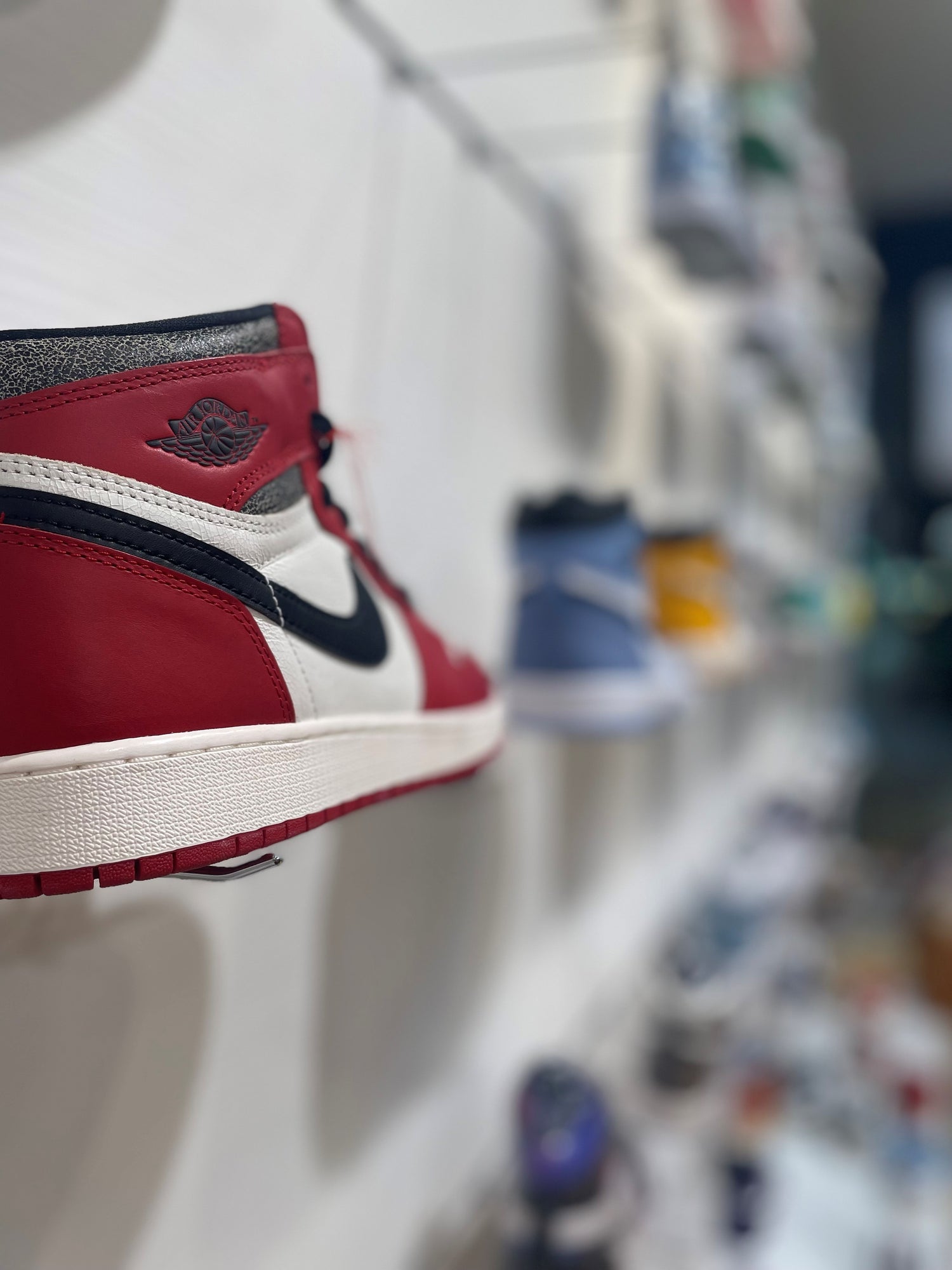 auf dem foto von der sneaker wand im ehemaligen store in bern ist im fokus der jordan 1 chicago lost and found. im hintergrund verschwommen mehr jordan modelle in bunten farben